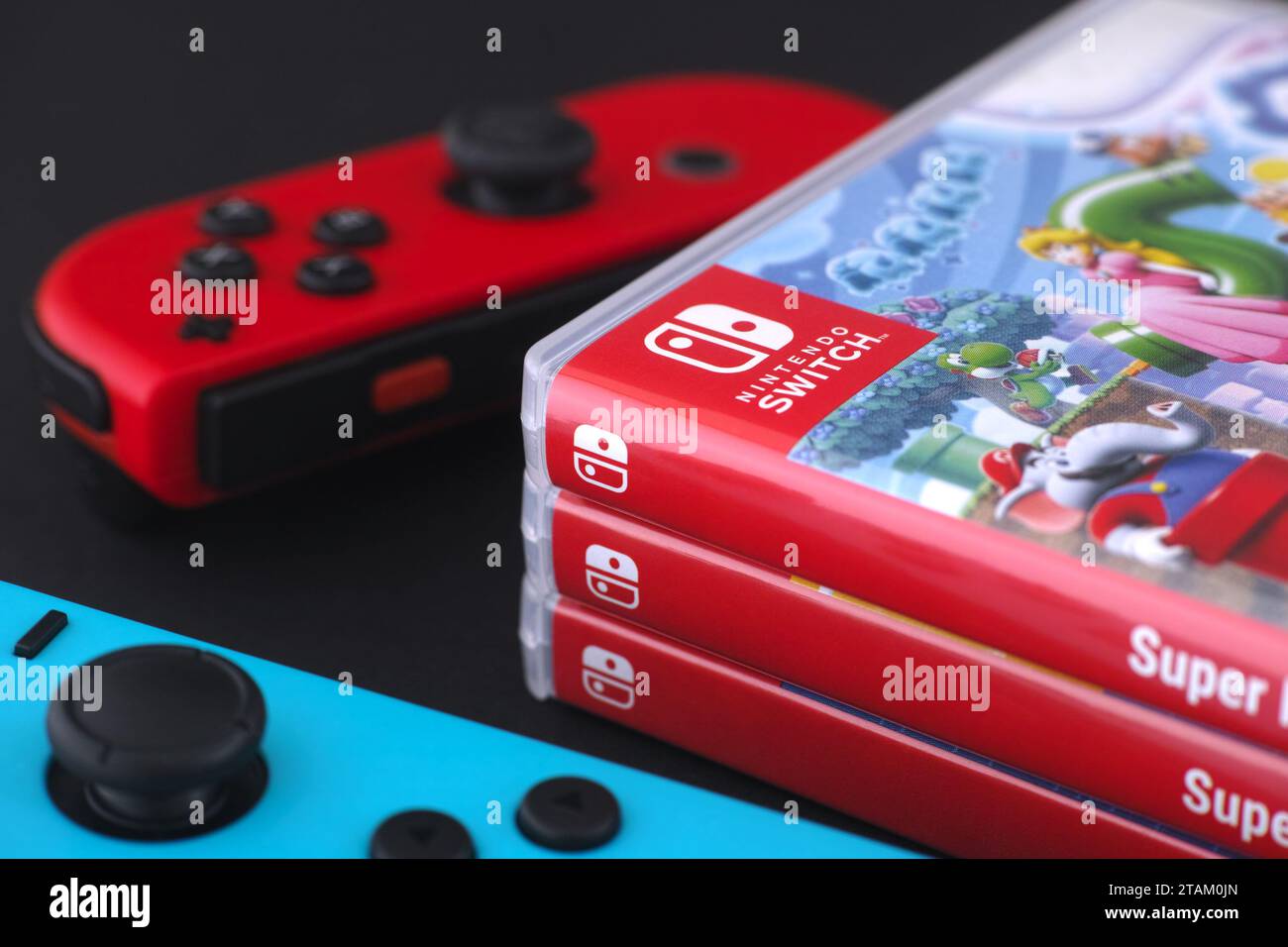 Tambov, Federazione Russa - 01 dicembre 2023 Un jolly con Nintendo Switch rosso e blu che si trovano vicino a una pila di giochi Nintendo Switch in box. Foto Stock