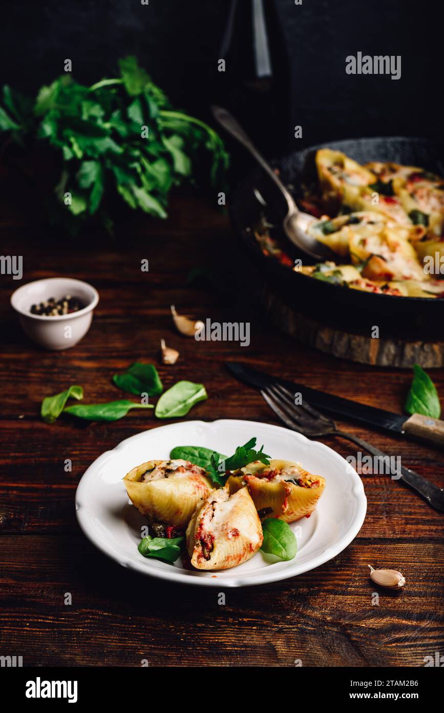 Conchiglie di jumbo al forno farcite con manzo macinato, spinaci e formaggio su piatto bianco Foto Stock