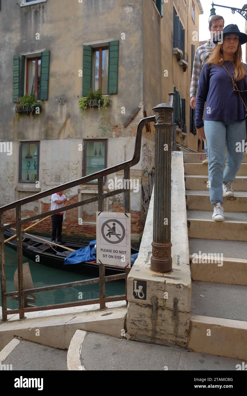 Segni di sovra-turismo che sorpassa Venezia e buone maniere: Non sederti, un cartello sulle scale del ponte, piccoli spazi dove i turisti possono riposare Foto Stock