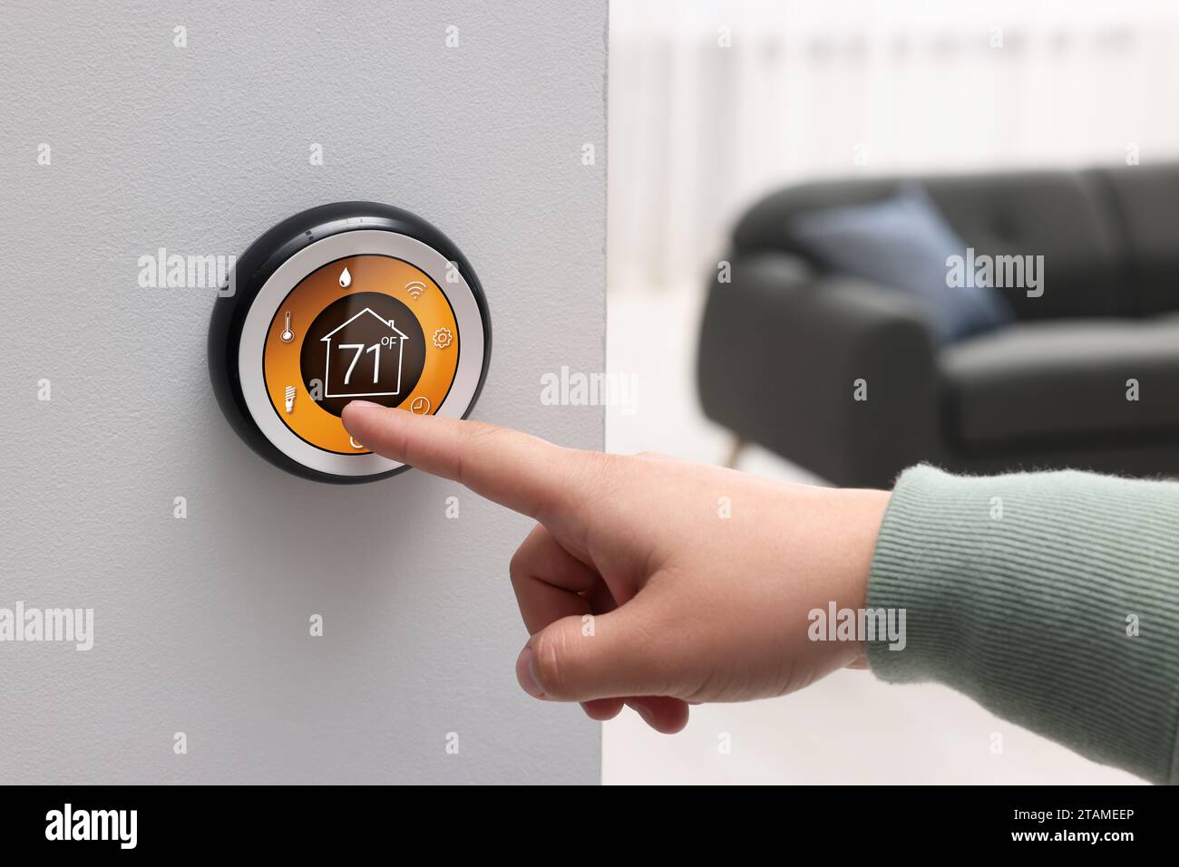 Sistema domestico intelligente. Donna che usa il termostato al chiuso, primo piano Foto Stock