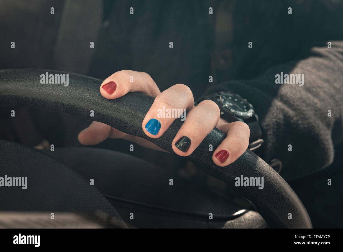 Primo piano di un uomo che indossa un orologio di lusso e tiene in mano il volante. Messa a fuoco selezionata. Un uomo con unghie dipinte. Design chiodi maschili. uomini manicur Foto Stock