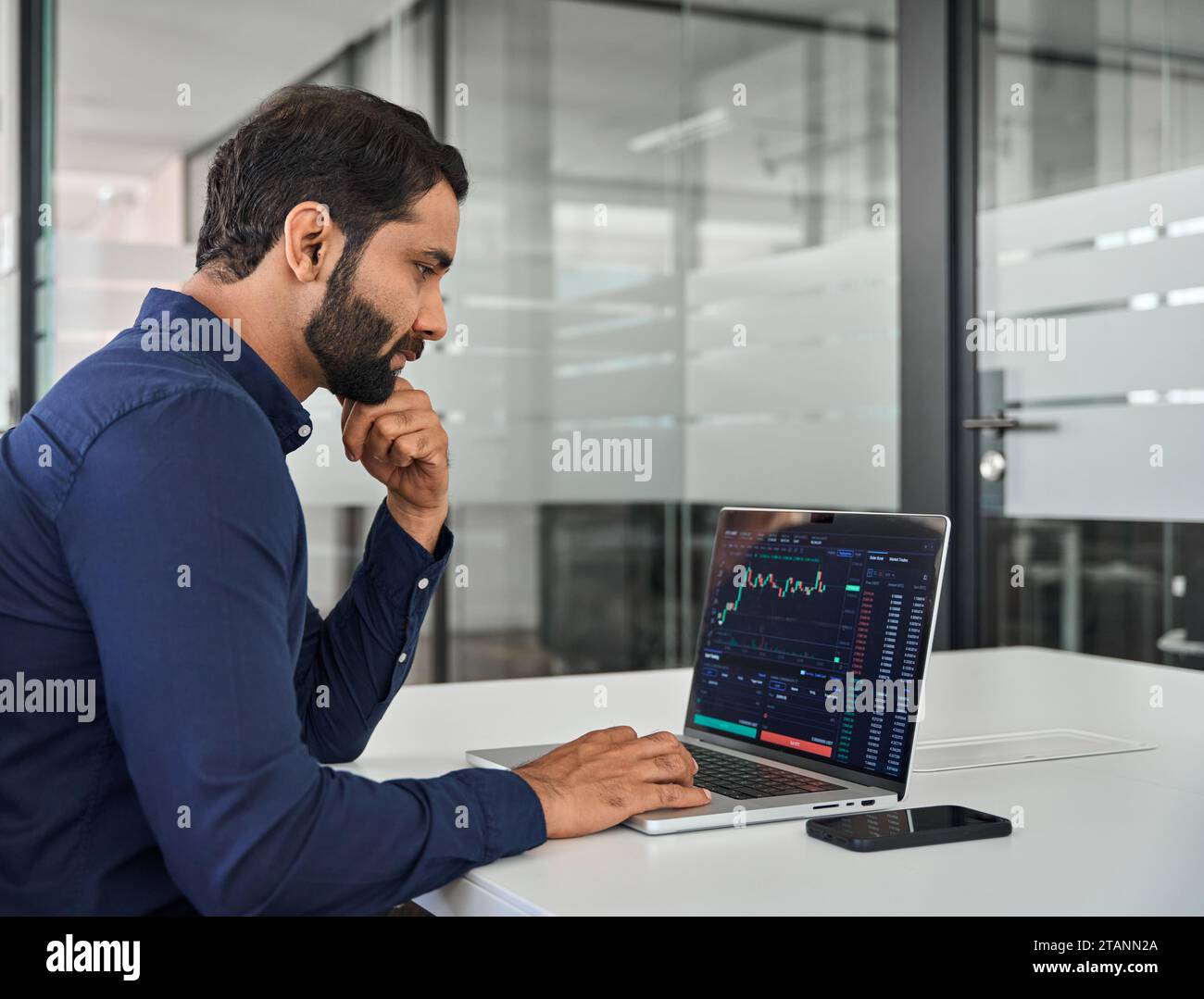 Un imprenditore indiano impegnato investitore in borsa che analizza il mercato degli investimenti. Foto Stock