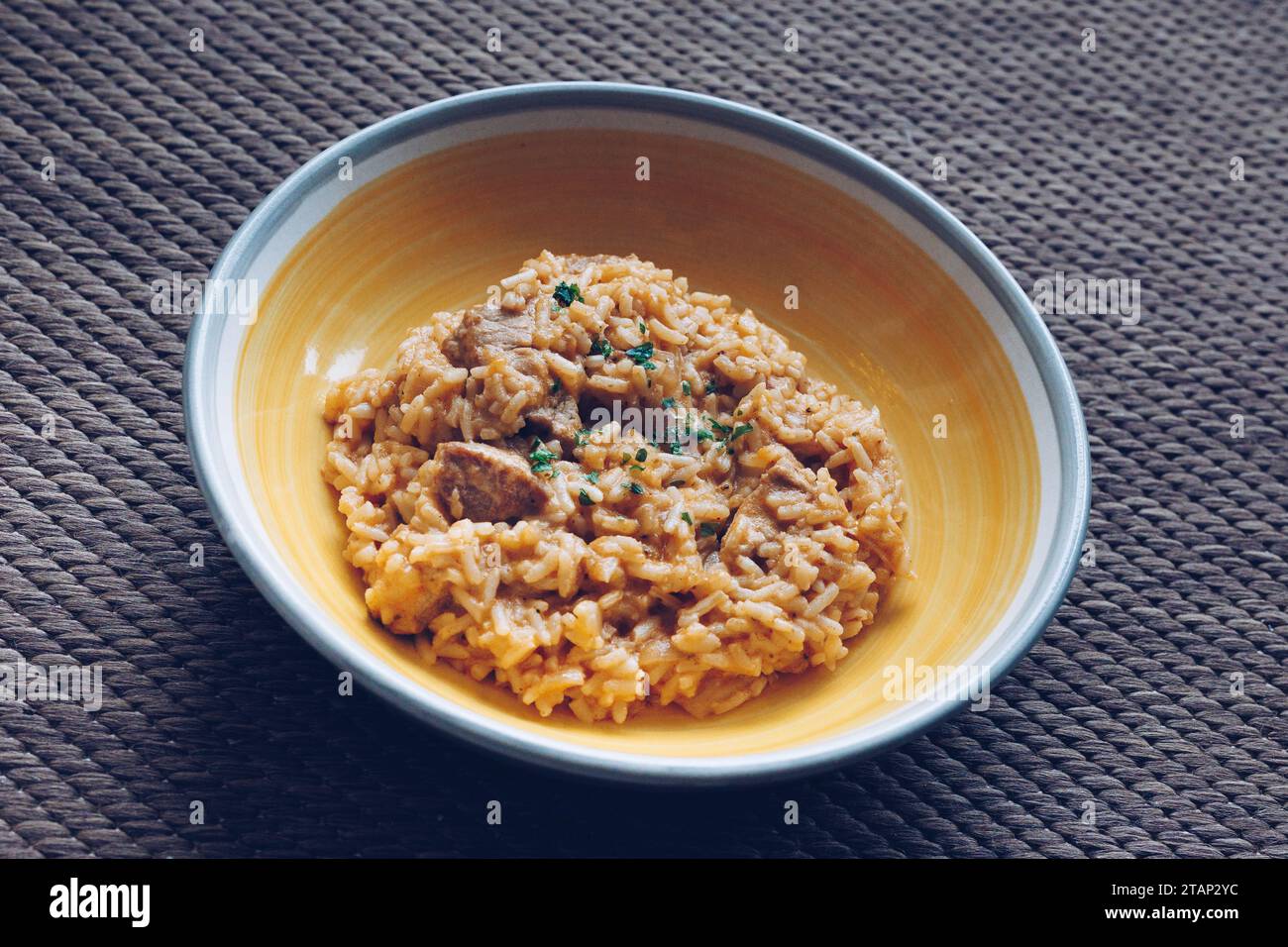 Piatto di carne di riso con maiale, servito su un piatto giallo. Cucinato in tradizionale stile austriaco serbo. Foto Stock