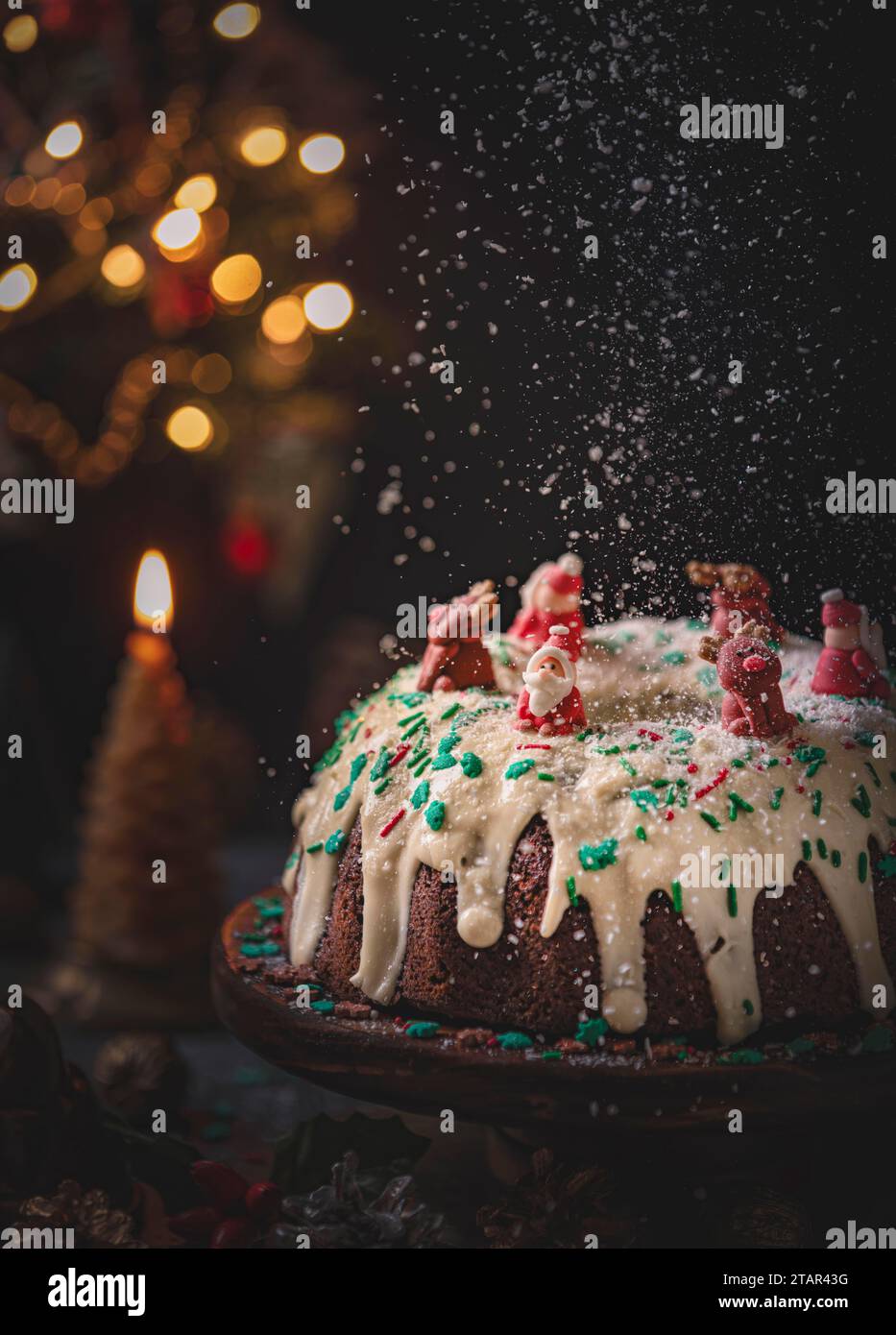 Torta, decorata per Natale, candele e luci delle fate sullo sfondo, zucchero cadente, fotografia di cibo Foto Stock