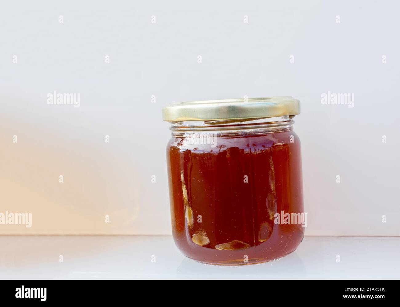 Il vasetto di vetro della piena di miele fresco con coperchio Foto Stock