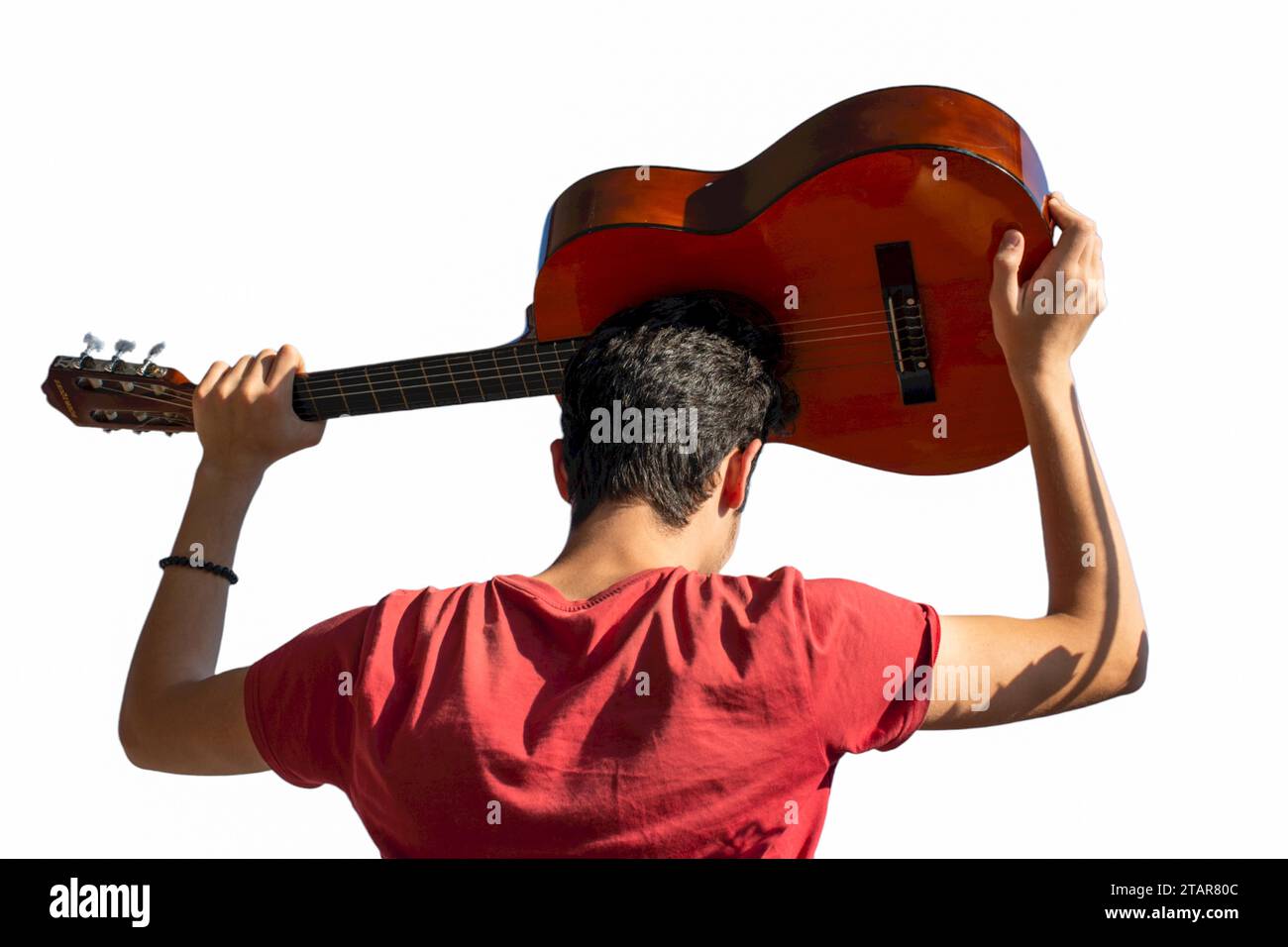 Giovane uomo salendo una chitarra acustica nel cielo blu Foto Stock