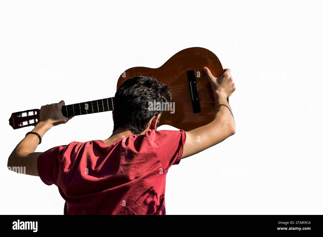 Giovane uomo salendo una chitarra acustica nel cielo blu Foto Stock
