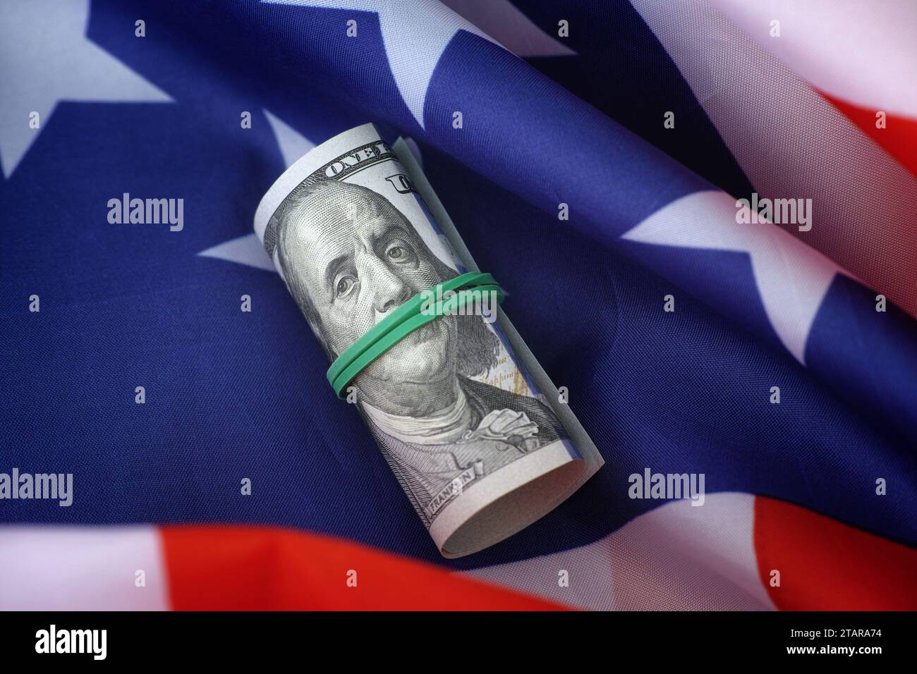 Una banconota da cento dollari che giace su una bandiera americana. Primo piano. Foto Stock