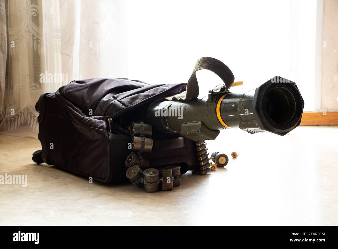 Un lanciagranate anticarro e cinture di mitragliatrici fuoriescono da una valigia sul pavimento in un appartamento in Ucraina, armi in valigia, viaggio, Foto Stock