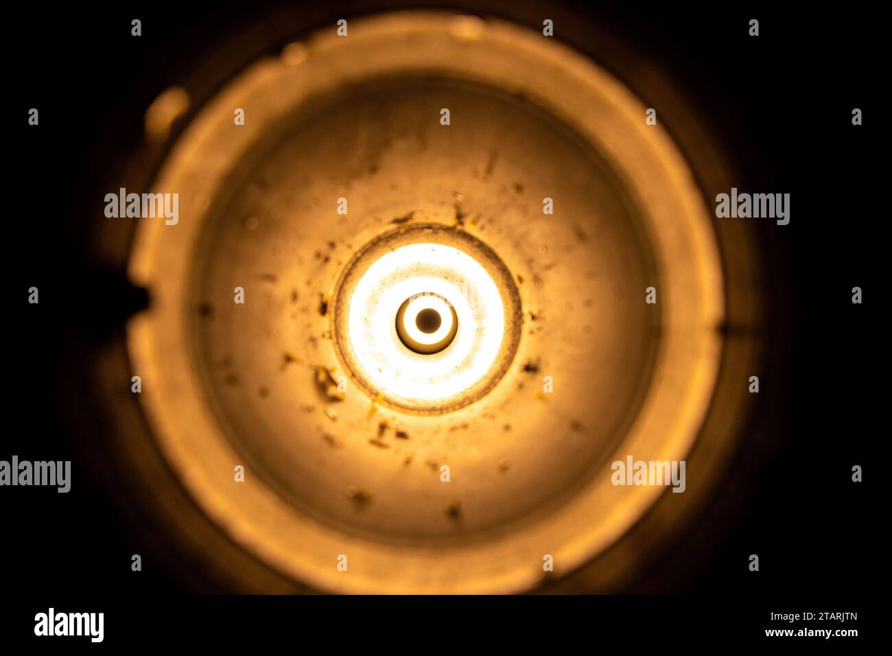 Torcia elettrica in un lanciagranate anticarro vuoto usato come sfondo, luce brillante in un cerchio, luce da un buco Foto Stock