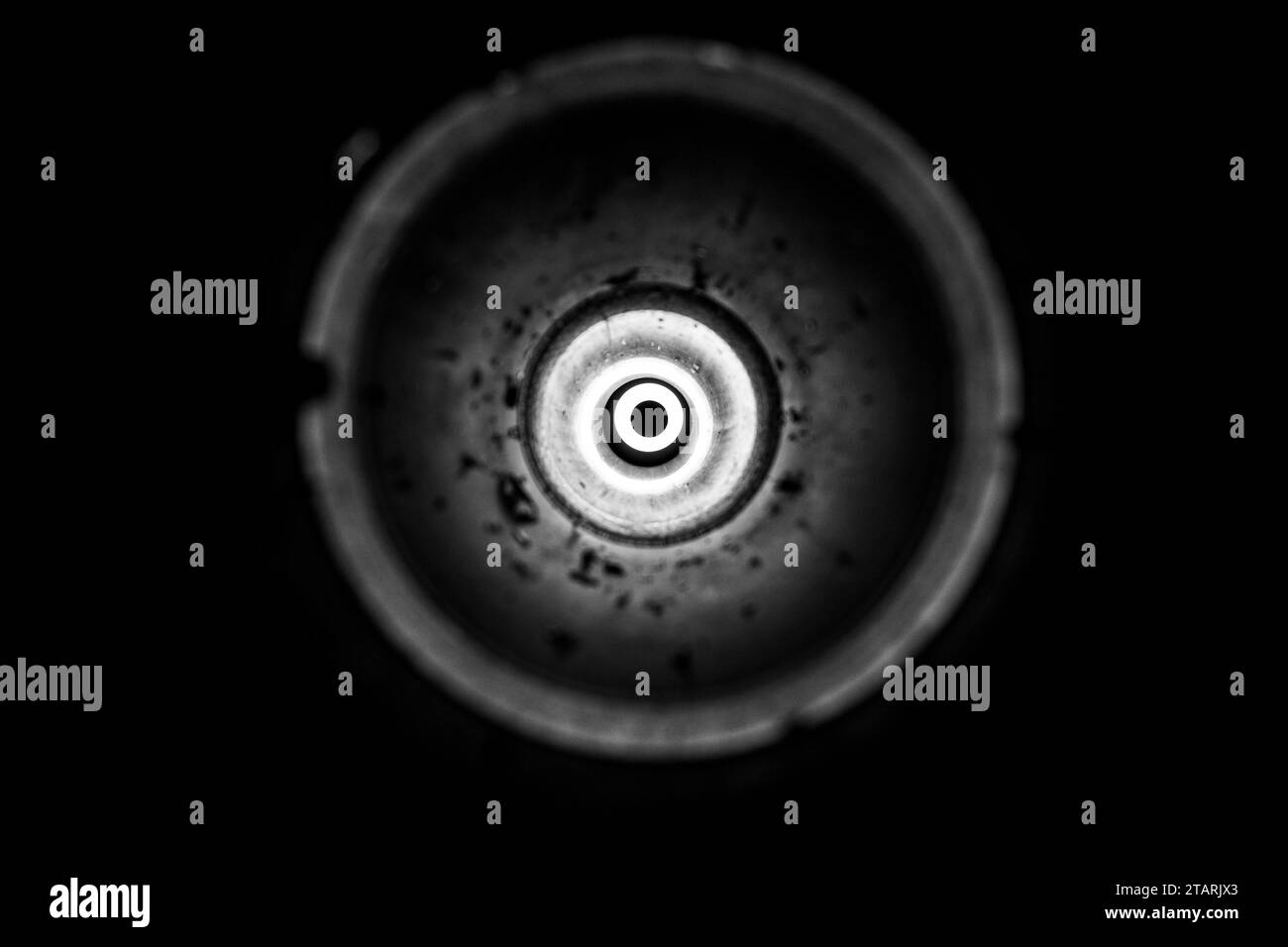Torcia in un lanciagranate anticarro vuoto usato come sfondo, luce brillante in cerchio, luce da un buco, foto in bianco e nero Foto Stock