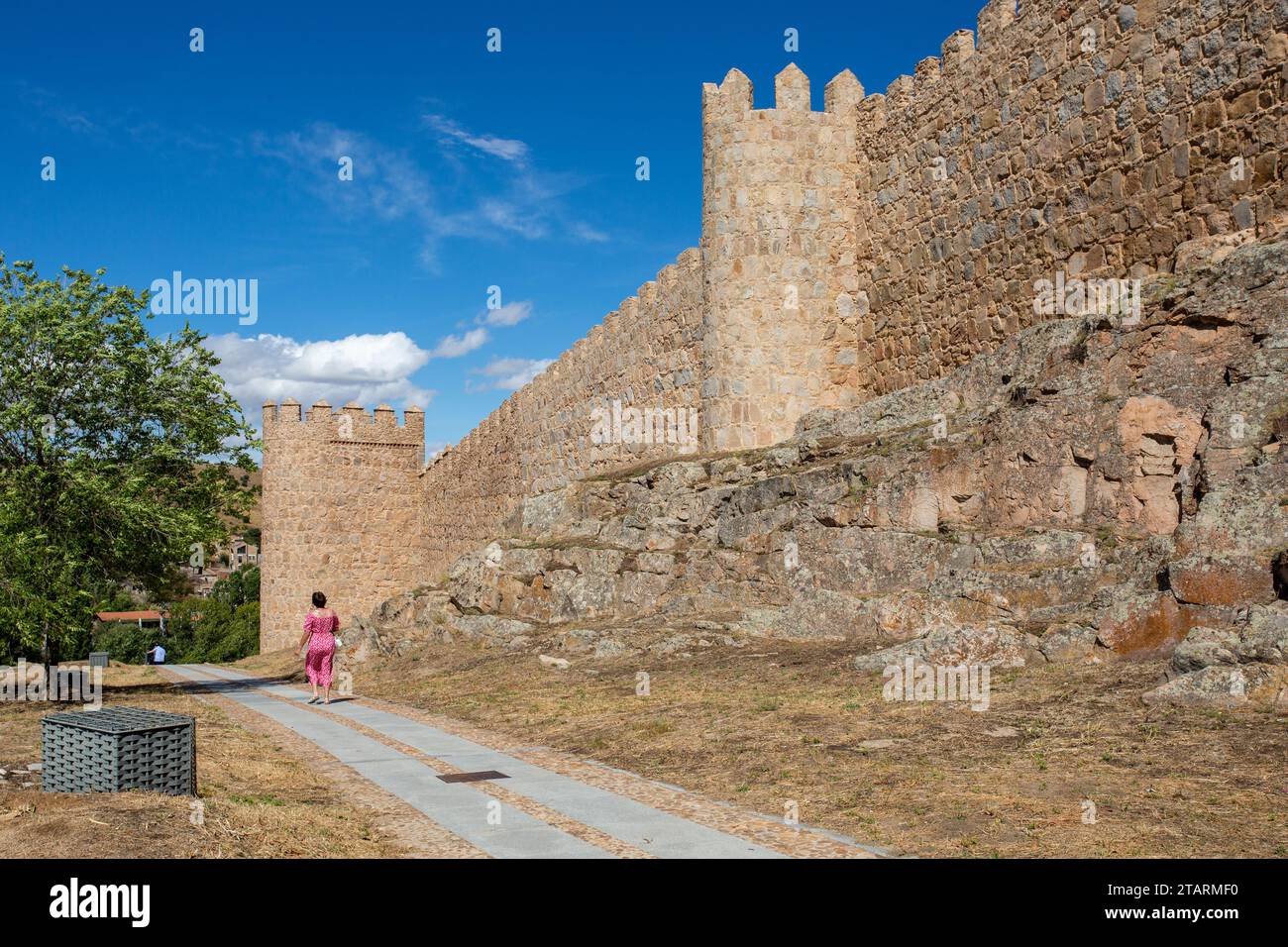 Donna che cammina accanto al bastione e alle fortificazioni nella città fortificata spagnola di Avila, nella comunità autonoma di Castiglia e León Spagna Foto Stock