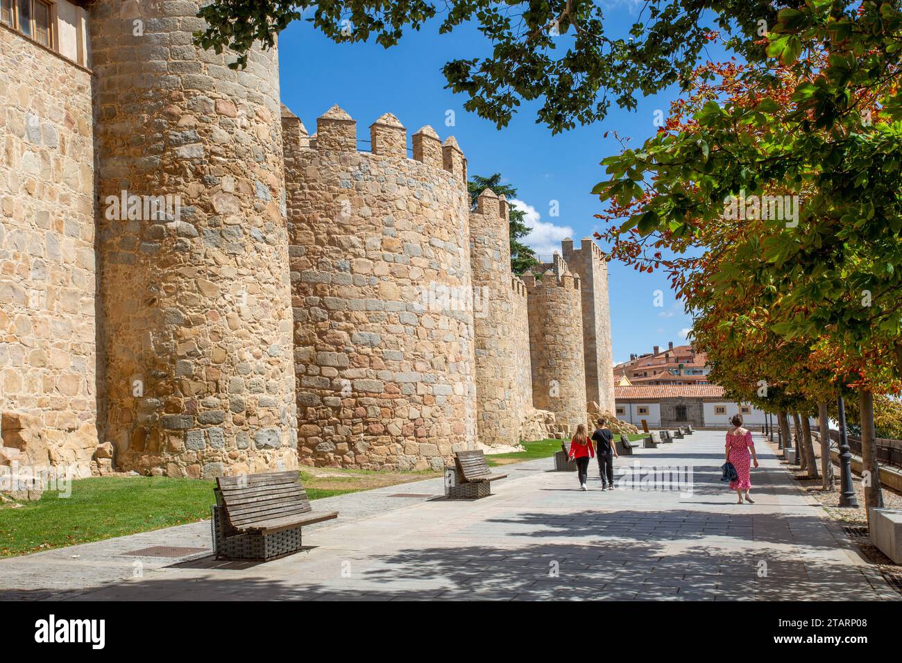 Gente che cammina accanto ai bastioni delle mura fortificate della città fortificata spagnola di Avila, nella comunità autonoma di Castiglia e León Spagna Foto Stock
