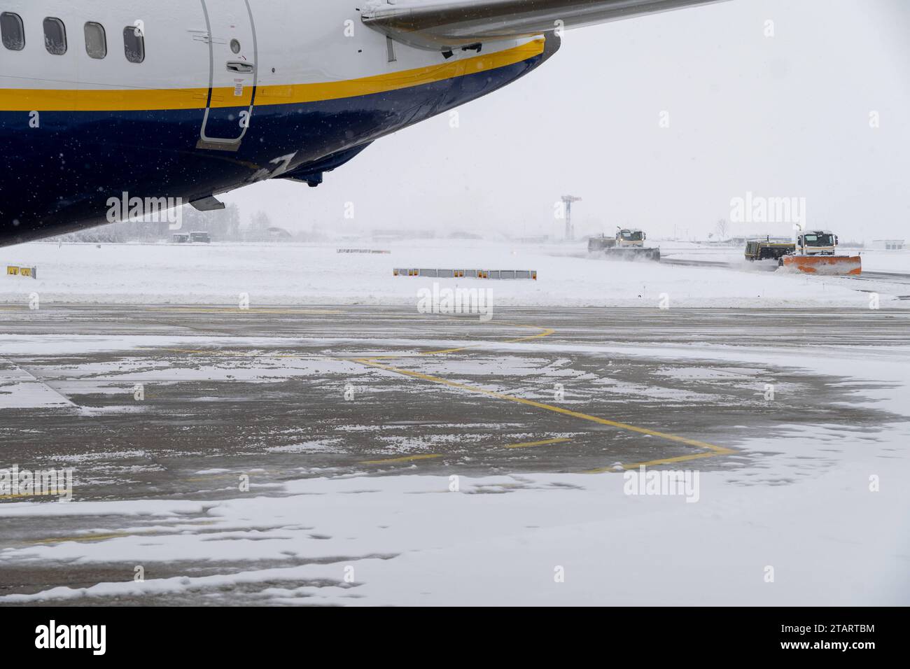 FMM, Baviera, Germania - 2 dicembre 2023: inizio dell'inverno e del caos della neve all'aeroporto in Baviera, spazzaneve e veicolo che attraversa i terreni dell'aeroporto intorno a un aereo Ryanair *** Wintereinbruch und Schneechaos auf dem Flughafen a Bayern, Schneepflug und Streufahrzeug fahren über das Flughafengelände um ein Flugzeug von Ryanair credito: Imago/Alamy Live News Foto Stock