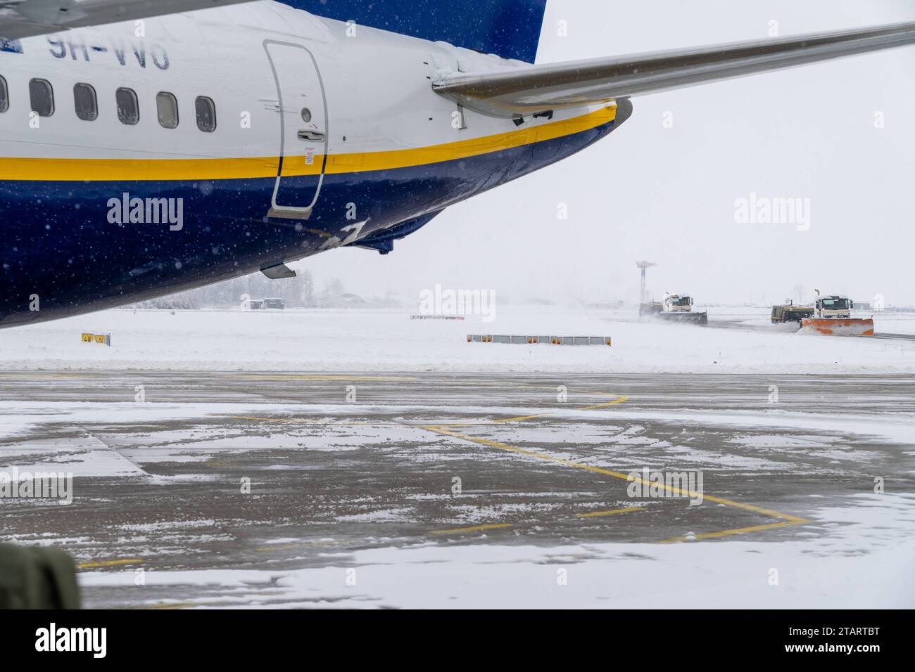 FMM, Baviera, Germania - 2 dicembre 2023: inizio dell'inverno e del caos della neve all'aeroporto in Baviera, spazzaneve e veicolo che attraversa i terreni dell'aeroporto intorno a un aereo Ryanair *** Wintereinbruch und Schneechaos auf dem Flughafen a Bayern, Schneepflug und Streufahrzeug fahren über das Flughafengelände um ein Flugzeug von Ryanair credito: Imago/Alamy Live News Foto Stock