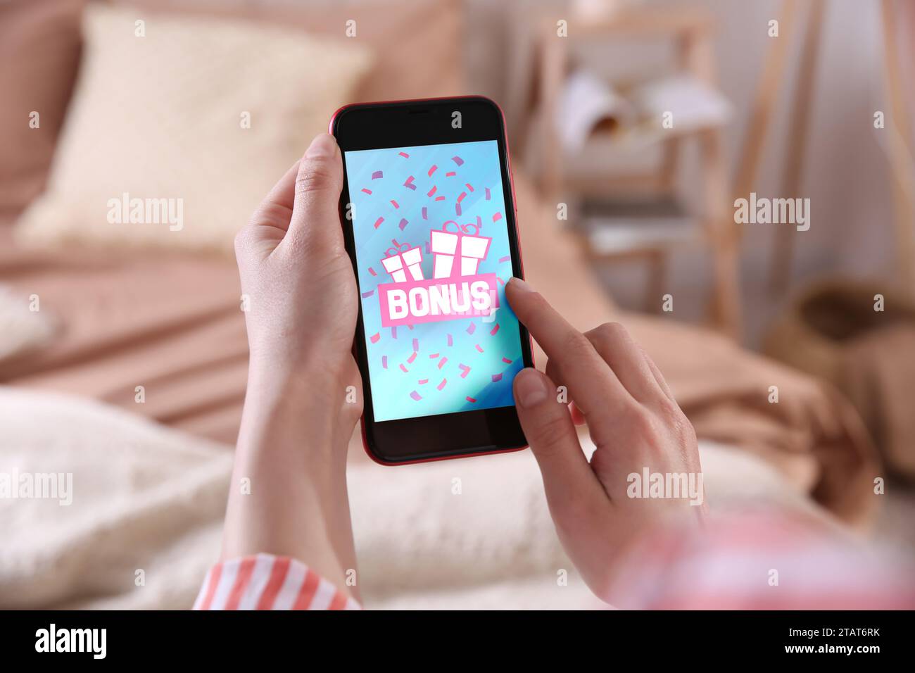 Guadagnare bonus. Donna che usa lo smartphone al chiuso, primo piano. Immagine di confezioni regalo, parole e coriandoli cadenti sullo schermo del dispositivo Foto Stock