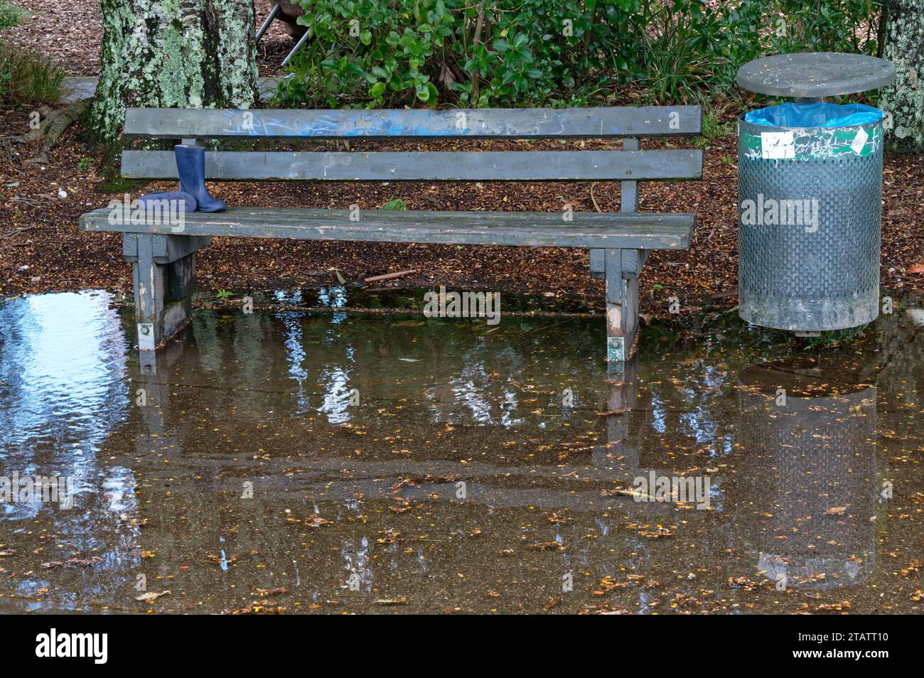 Un sedile e un cestino dei rifiuti sono bloccati in un'ampia pozzanghera o in un'area allagata dopo una forte pioggia Foto Stock