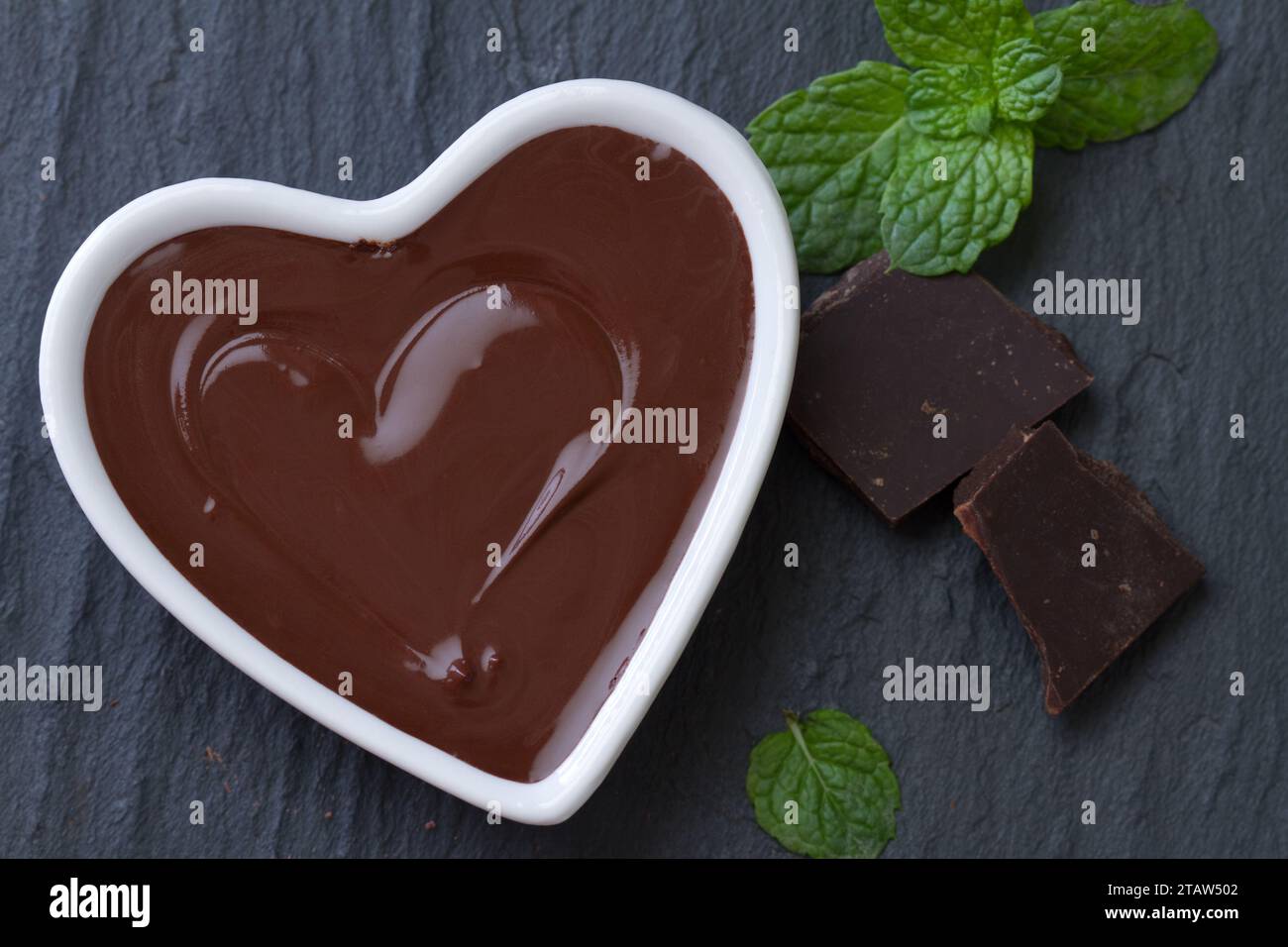Deliziosa mousse al cioccolato con menta in un recipiente a forma di cuore su sfondo scuro Foto Stock