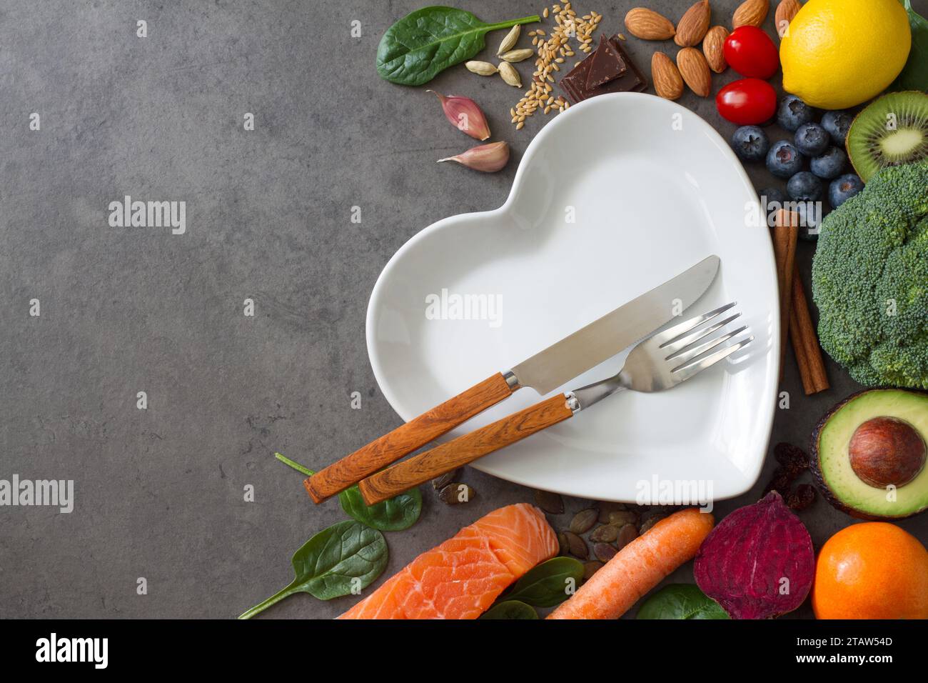 Prodotti naturali assortiti per un cuore sano, sfondo alimentare con piatti e posate, concetto di stile di vita sano Foto Stock