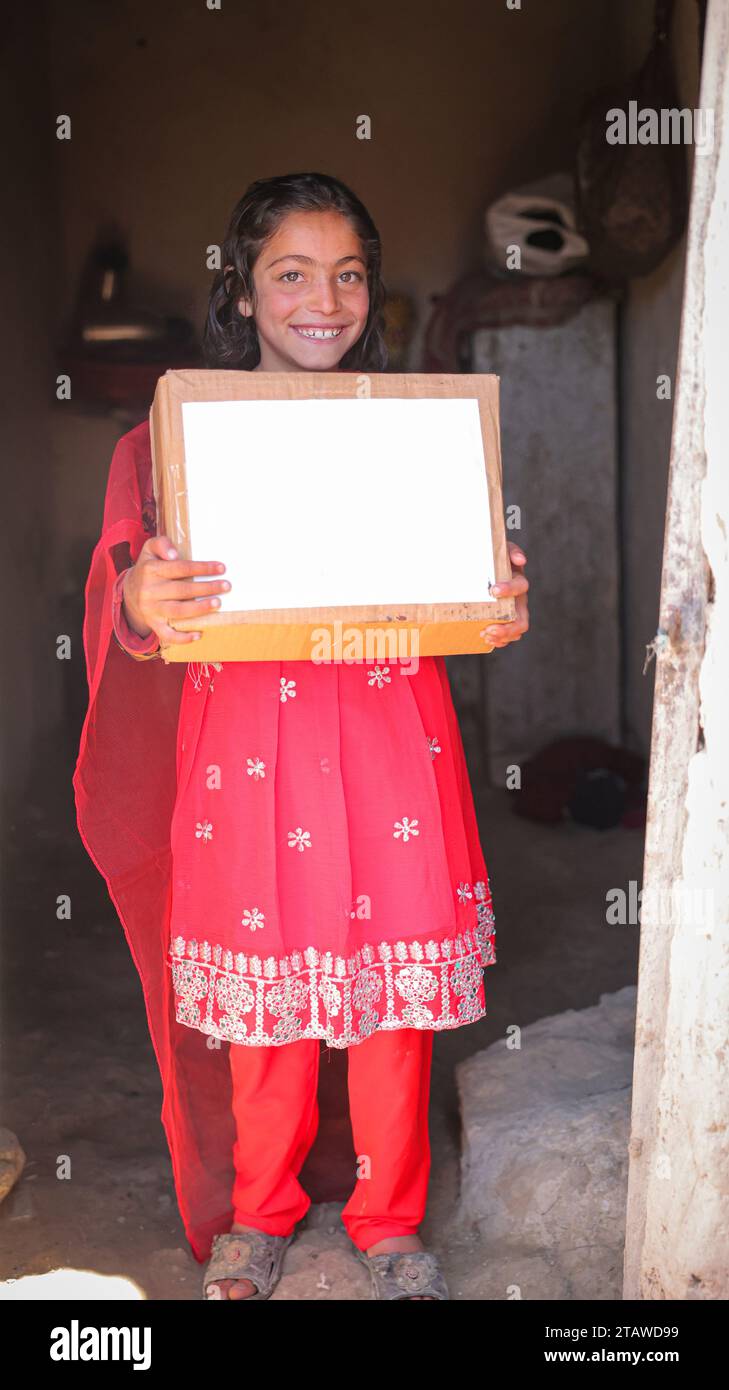 Ragazza afghana bisognosa che riceve donazioni | bambini che esprimono felicità dopo aver ricevuto pacchi di cibo per gli aiuti | bambini bisognosi che tengono un pacchetto di aiuti Foto Stock