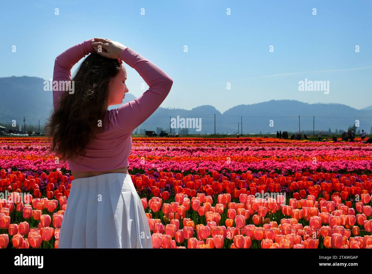 Una ragazza che gioca in un giardino fiorito con l'arcobaleno Foto Stock