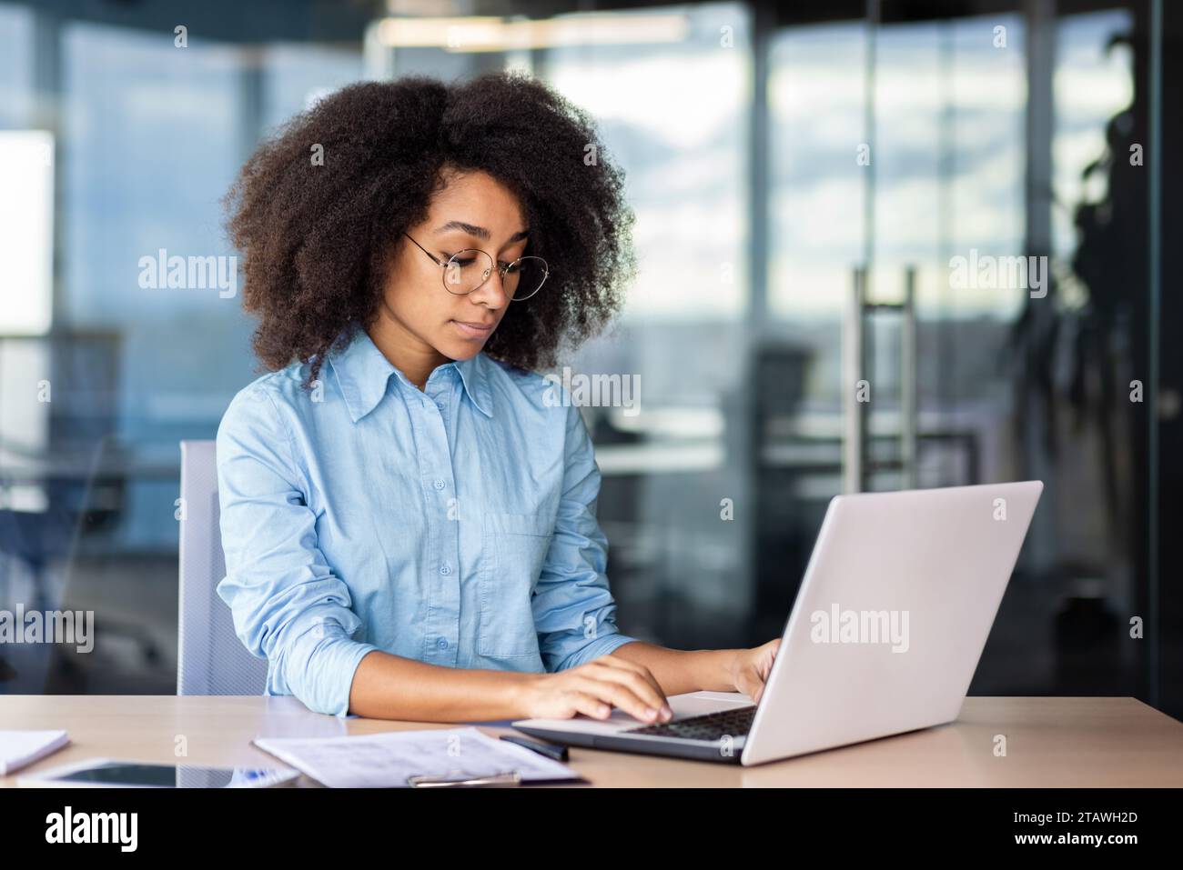 Donna attenta al pensiero serio sul posto di lavoro all'interno dell'ufficio che lavora con un notebook, donna d'affari che digita sulla tastiera. Foto Stock