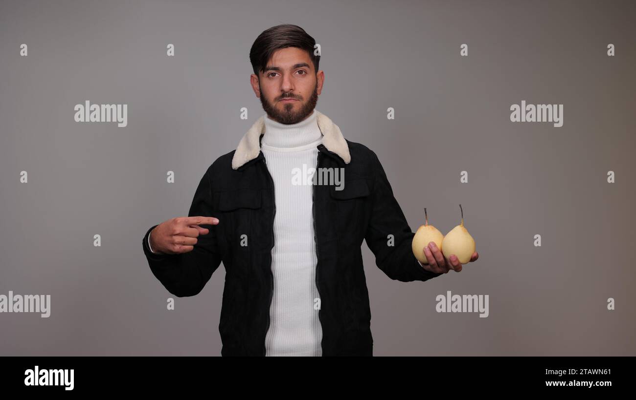 Un giovane che tiene pere e incoraggia la gente a mangiare pere. Foto Stock