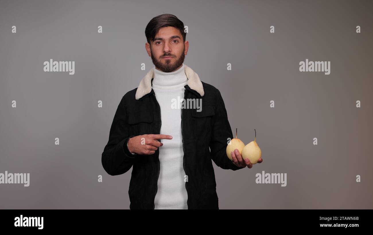 Un giovane che tiene pere e incoraggia la gente a mangiare pere. Foto Stock