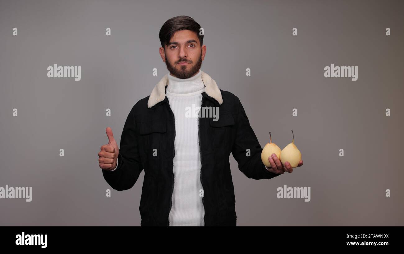 Un giovane che tiene pere e incoraggia la gente a mangiare pere. Foto Stock