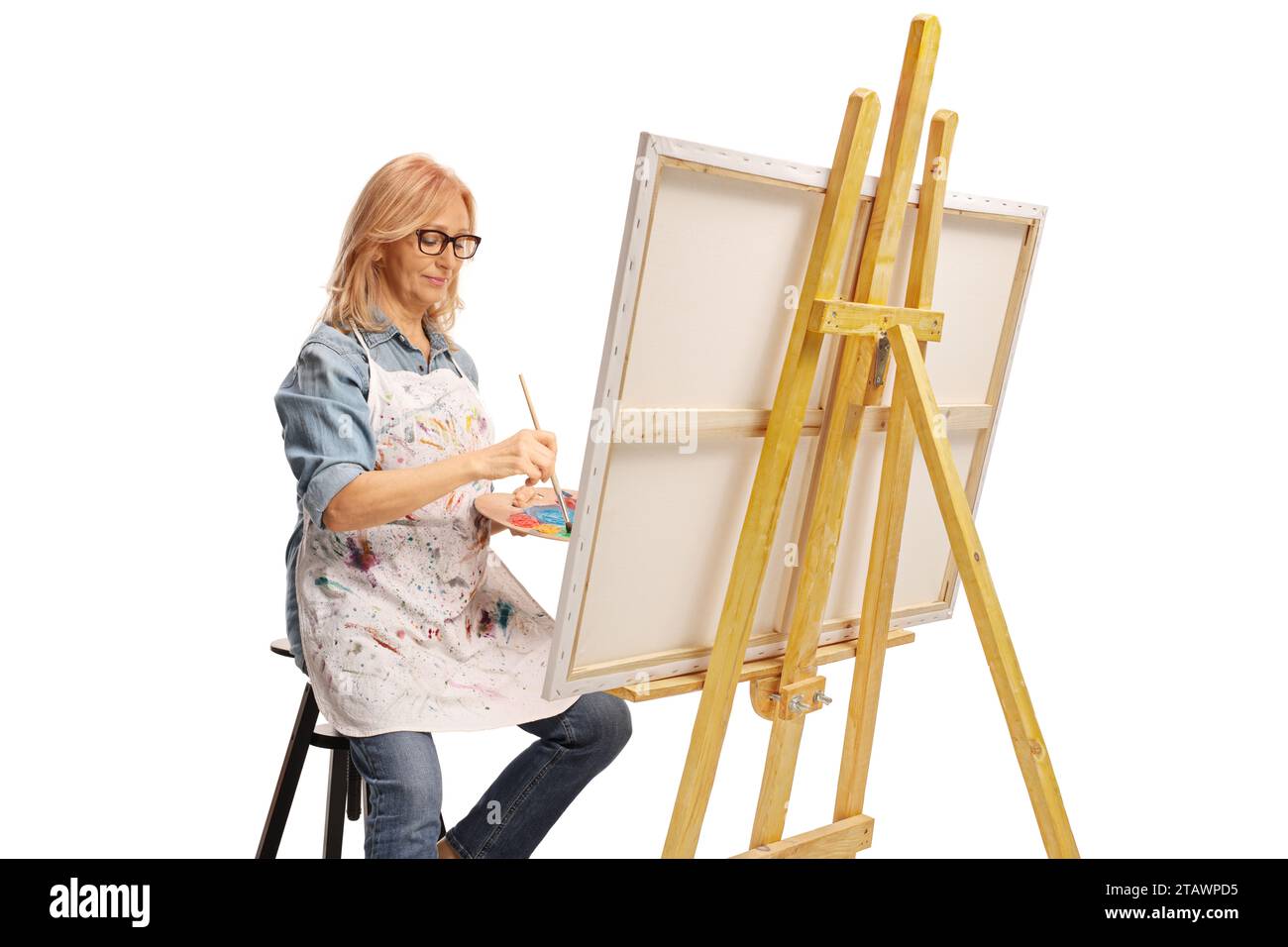 Donna di mezza età con un pennello e una tavolozza su una tela isolata su sfondo bianco Foto Stock