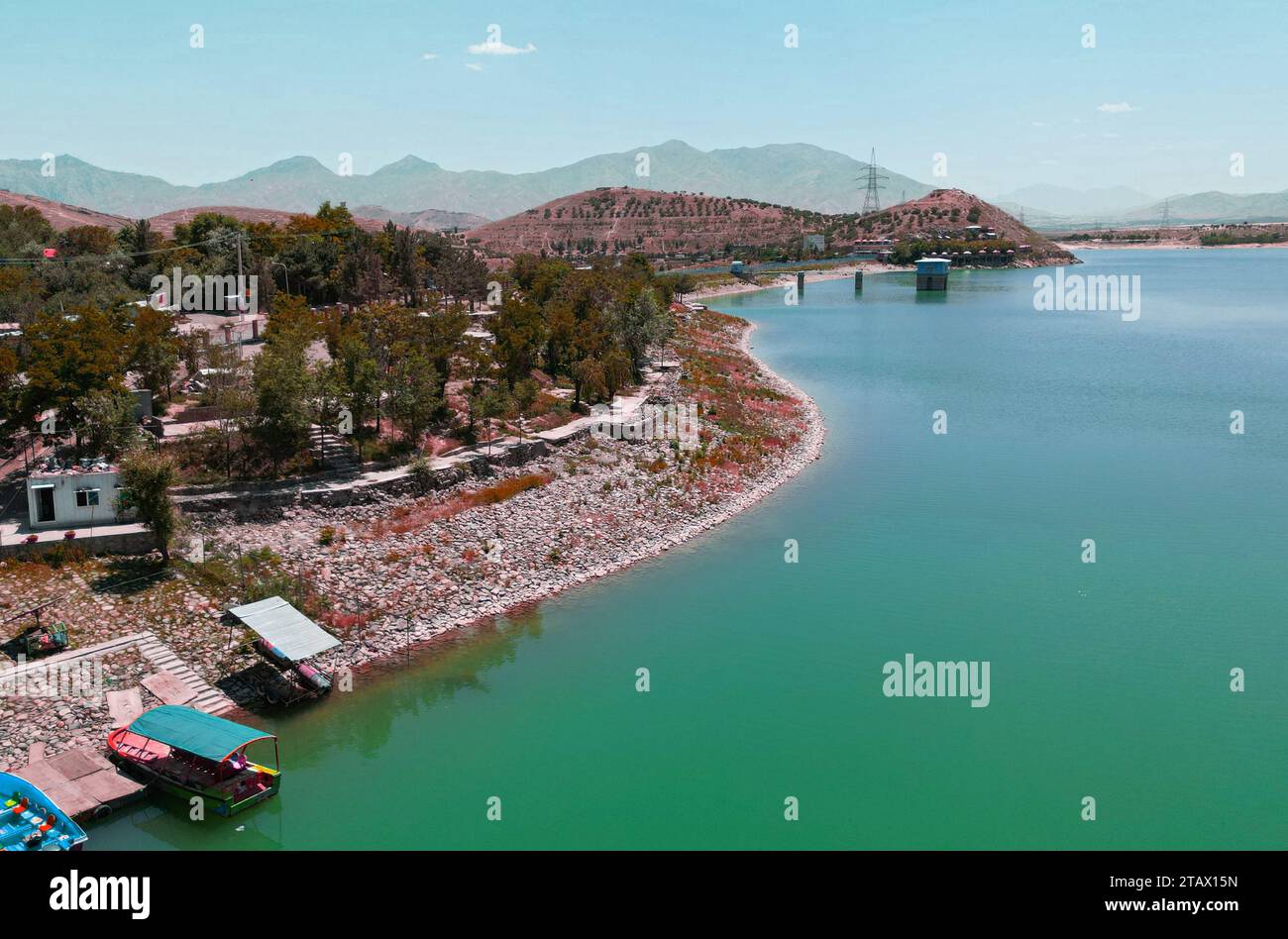 Un fiume che scorre attraverso un villaggio verde e montagne in Afghanistan Foto Stock