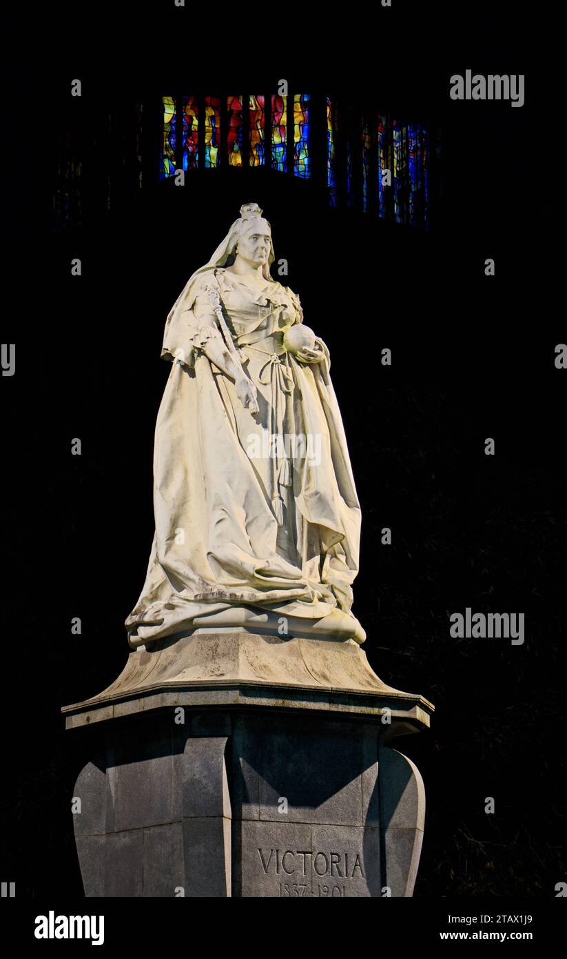 La statua della regina Vittoria, con le finestre illuminate della cattedrale di Blackburn sullo sfondo. Nella foto di notte Foto Stock