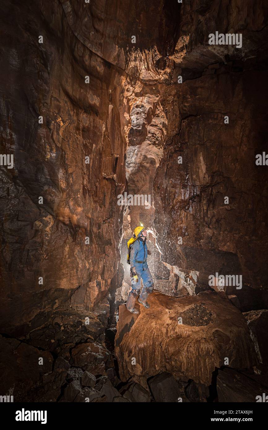 Cavatrice femmina con acqua in caduta a Ogof Ffynnon DDU, Galles, Regno Unito Foto Stock