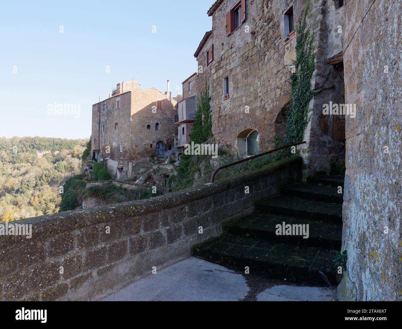 Parte esterna del centro storico di Calcata con mura in pietra vista da un sentiero con gradini, regione Lazio, Italia, 3 dicembre 2023 Foto Stock