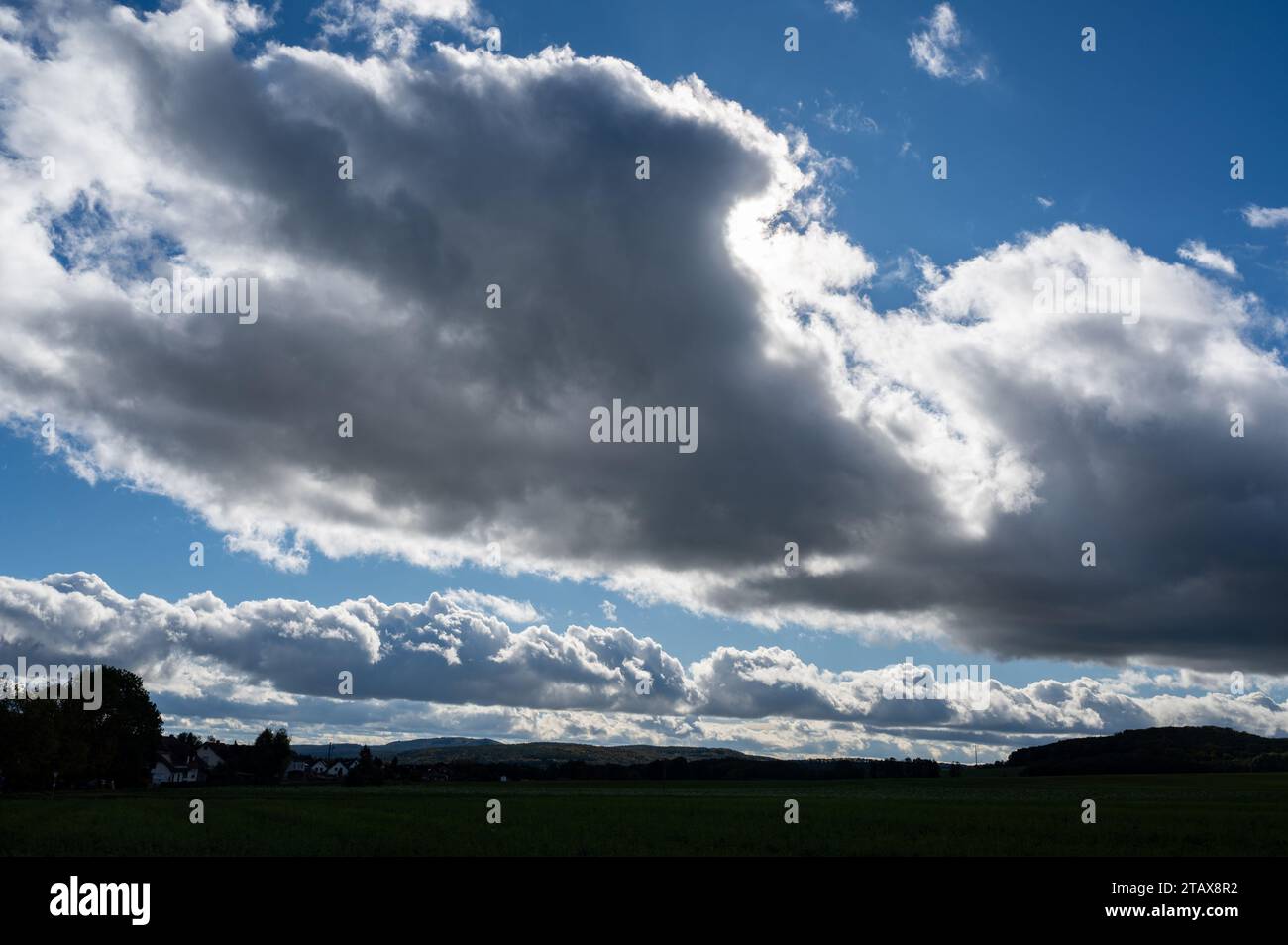 Le nuvole scure si stanno raccogliendo con il cielo blu e il paesaggio verde Foto Stock