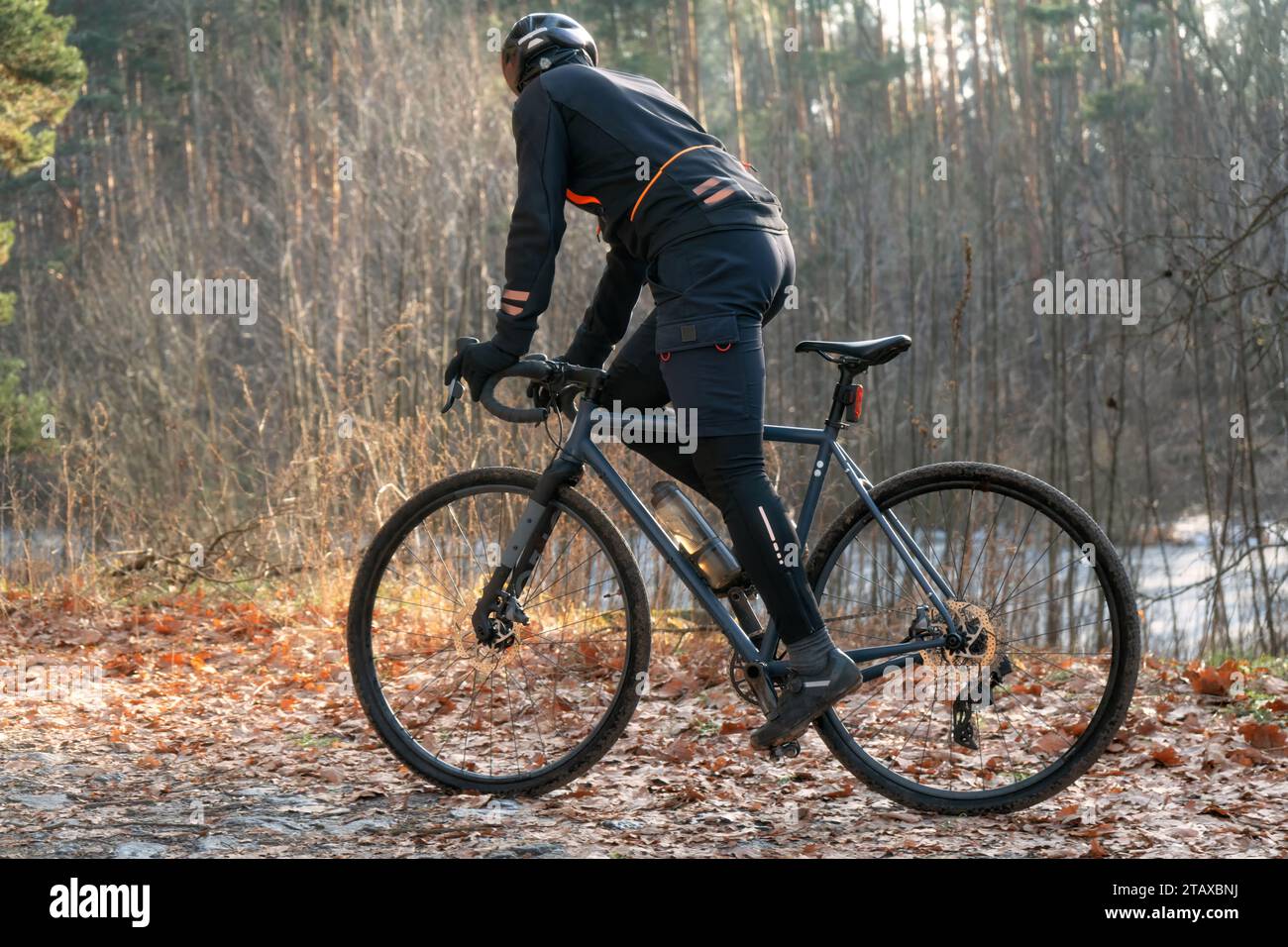 Ciclista professionista con abbigliamento sportivo e caschi su un sentiero nella foresta autunnale. Foto Stock