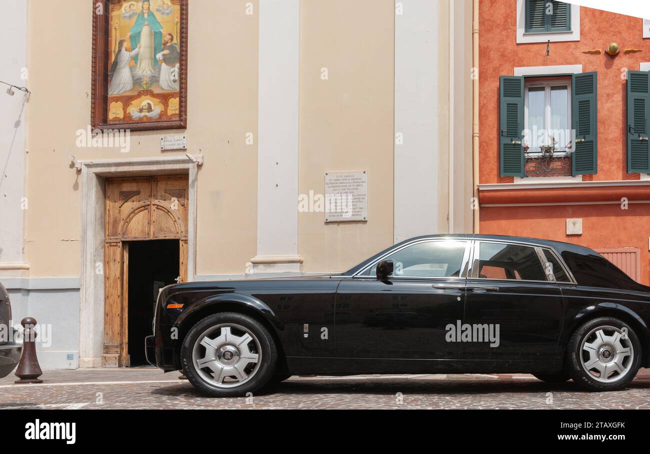 Monaco 2 maggio 2011; carrozza editoriale-Black Rolls Royce parcheggiata in strada acciottolata sotto quadro religioso sul muro fuori dalla piccola cappella . Foto Stock