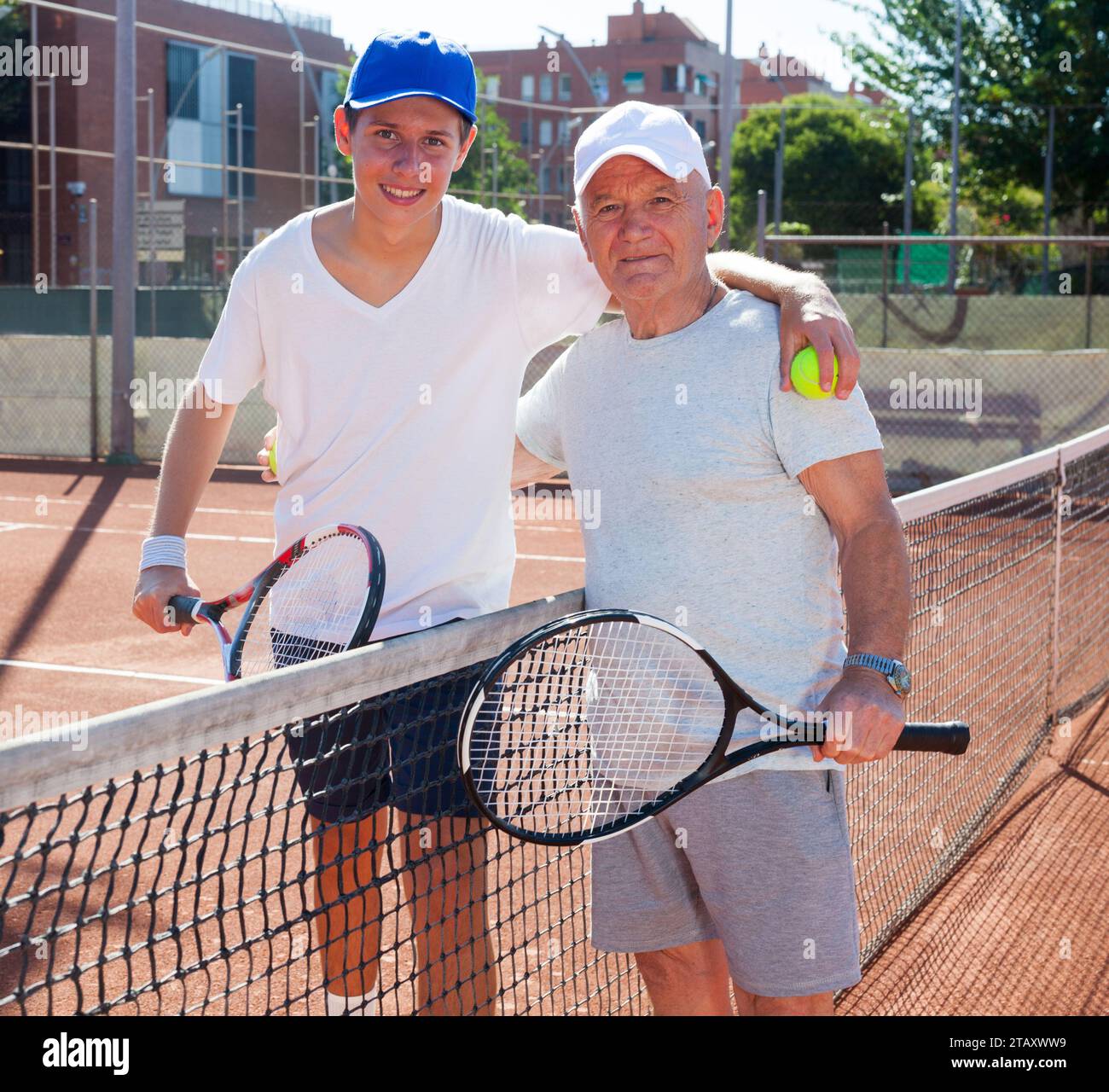 Nonno e nipote in posa sul campo da tennis Foto Stock