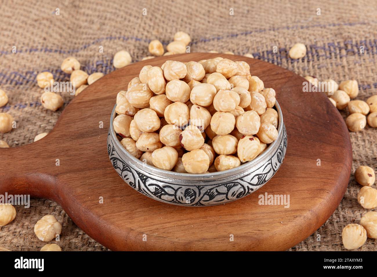 Varietà di nocciole in ciotola di rame su fondo di lino. Nocciole tostate sgusciate, nocciole sgusciate e nocciole tostate senza guscio. Cibo sano conc Foto Stock