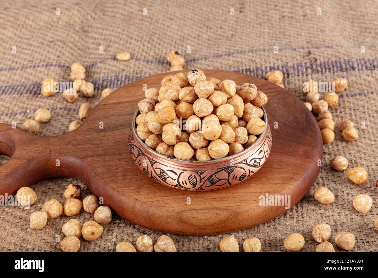 Varietà di nocciole in ciotola di rame su fondo di lino. Nocciole tostate sgusciate, nocciole sgusciate e nocciole tostate senza guscio. Cibo sano conc Foto Stock