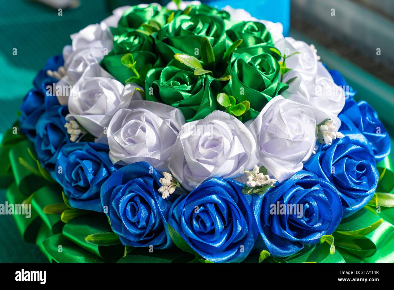 Ornamento realizzato con fiori tessili verdi bianchi e blu Foto Stock