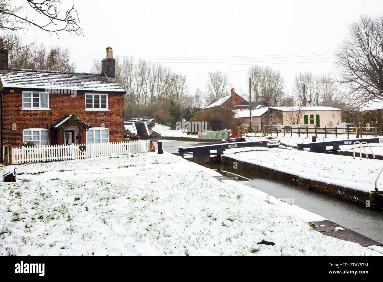 Cottage con canale chiuso e narrowboat sulla neve in inverno sul canale Trent e Mersey a Wheelock, Inghilterra, Regno Unito Foto Stock