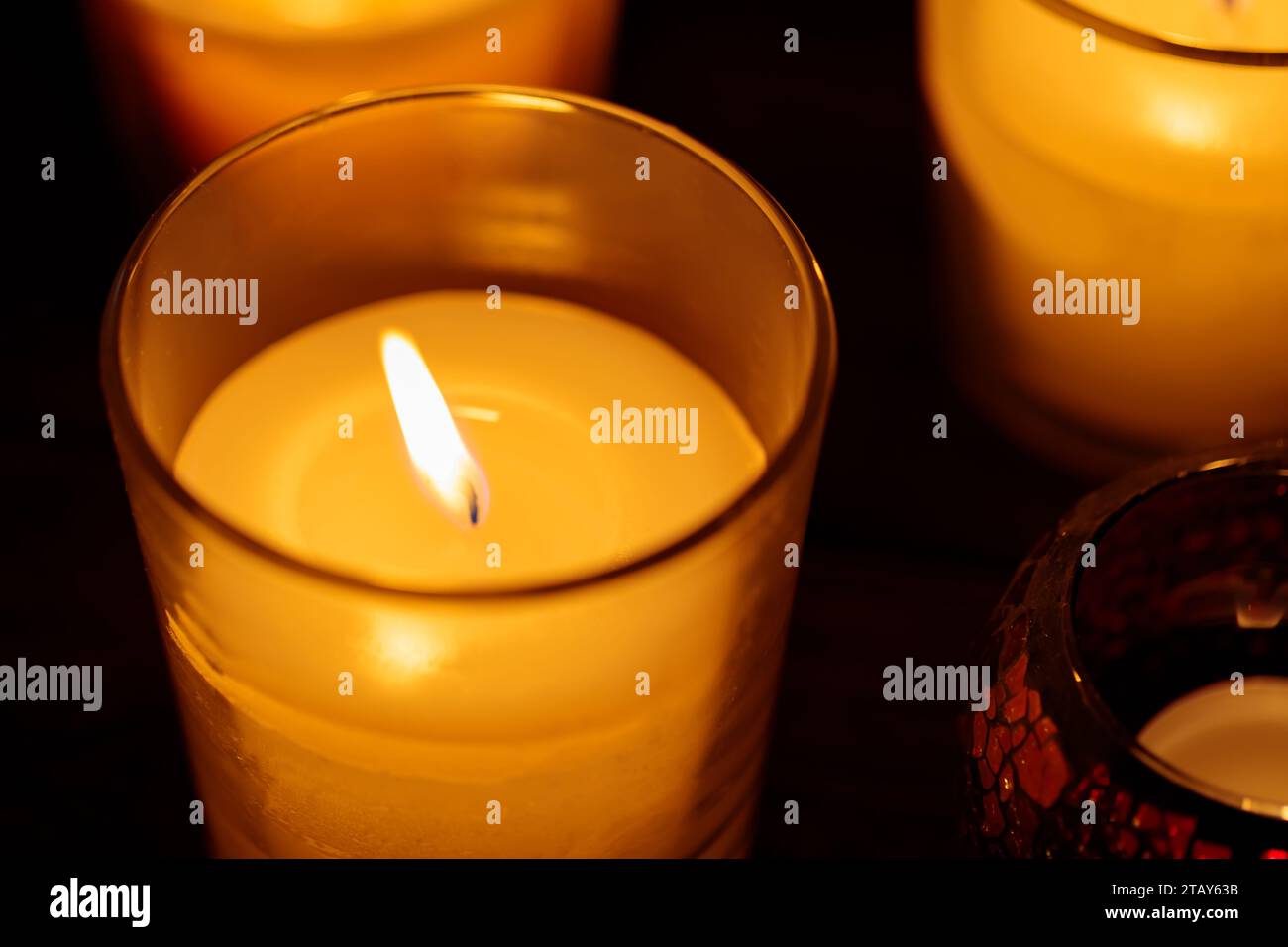 Candele aromatiche in vetro: Luce calda su sfondo scuro, primo piano Foto Stock