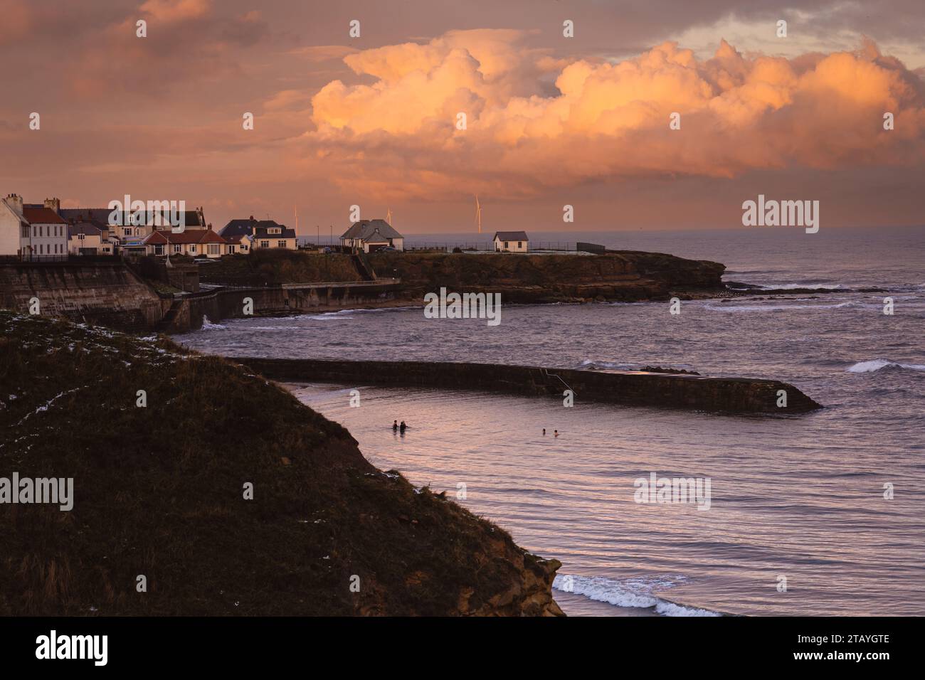 Guardando a nord attraverso la baia di Cullercoats al tramonto con la neve a terra Foto Stock