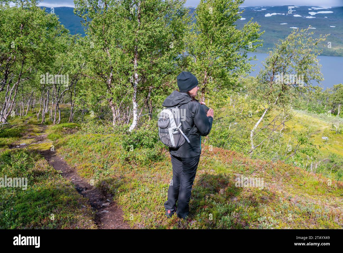 Una donna matura farà delle foto con il cellulare sopra le montagne e il lago mentre cammina sulle montagne norvegesi e sulle betulle selvagge di montagna. Vita sana Foto Stock