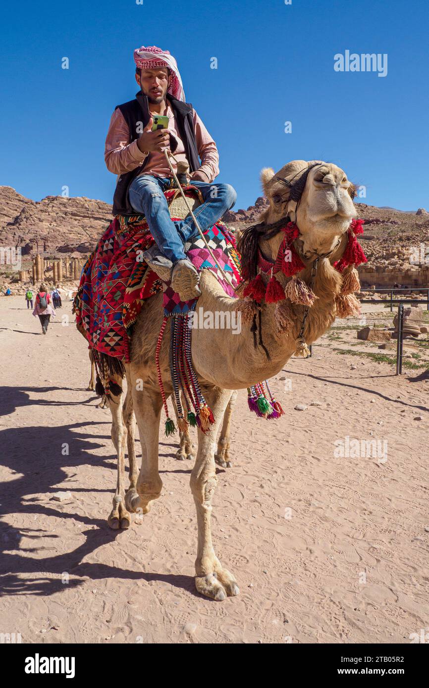 Cammello e cavaliere sul suo telefono, il parco archeologico di Petra, un sito patrimonio dell'umanità dell'UNESCO, 7 nuove meraviglie del mondo, Giordania. Foto Stock