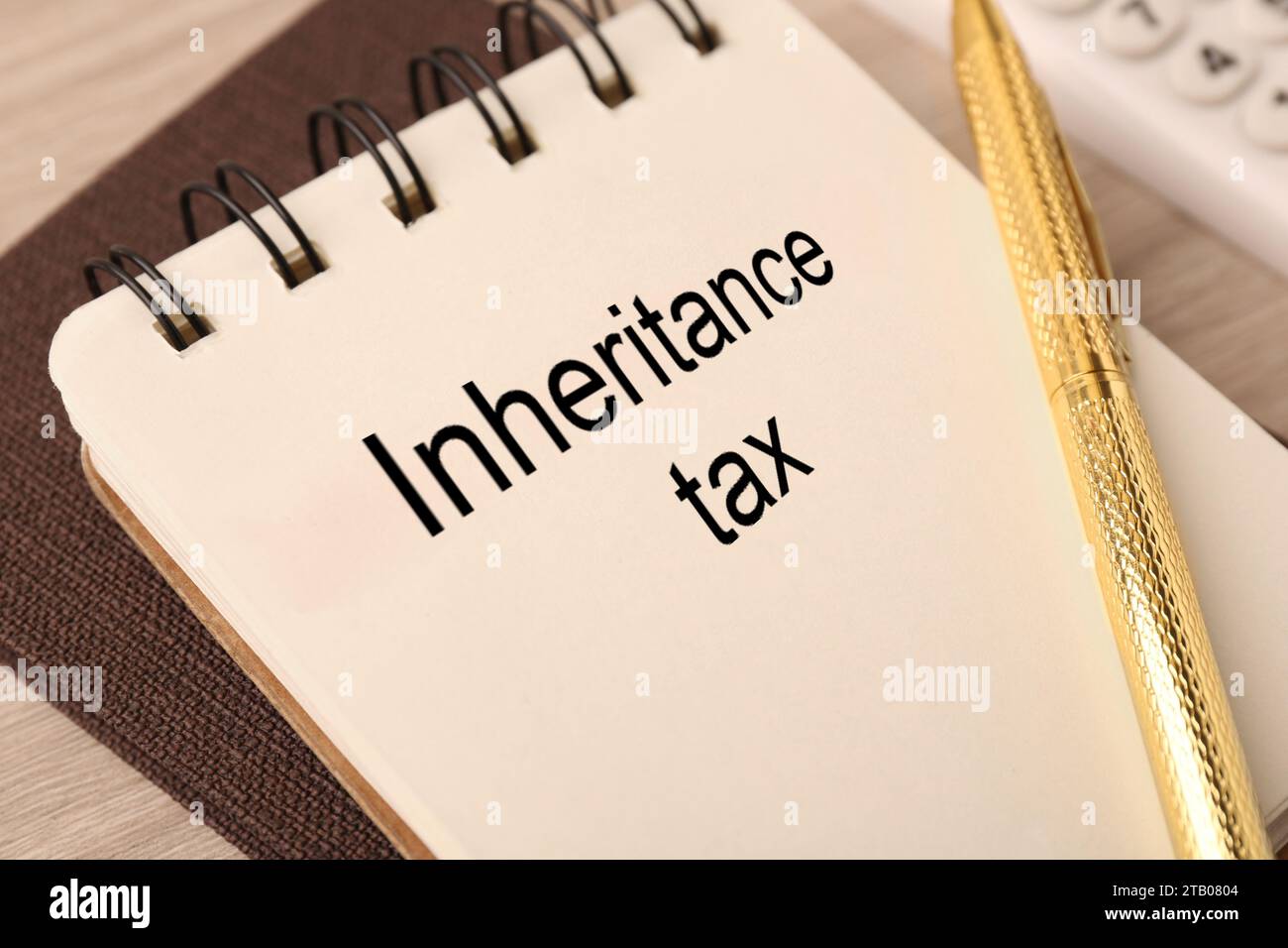 Blocco note con frasi Inheritance Tax e penna su un tavolo di legno, primo piano Foto Stock