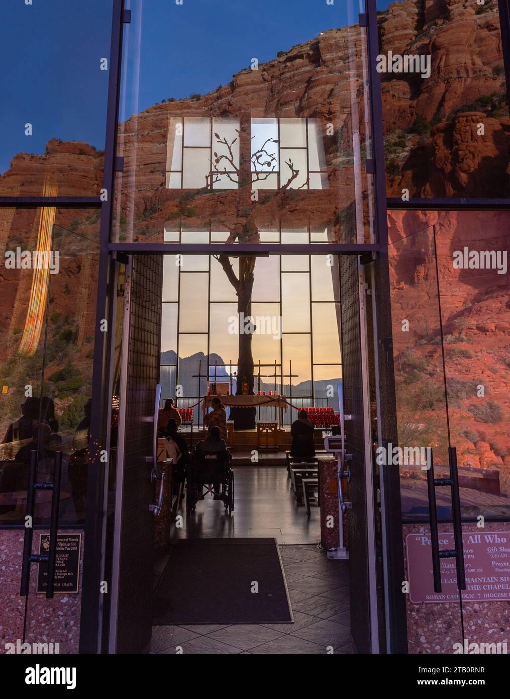 Persone all'interno della famosa Cappella della Santa Croce con roccia rossa e cielo blu riflessi nelle porte d'ingresso della finestra di vetro. Sedona, Arizona sud-ovest degli Stati Uniti Foto Stock