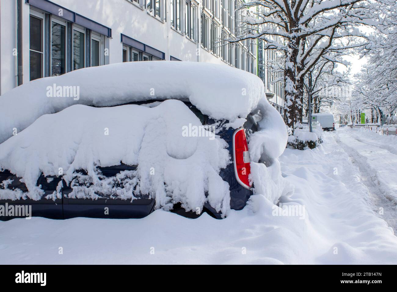 Un'auto parcheggiata è coperta di neve dopo una nevicata. Tempo invernale a Monaco, aumento delle precipitazioni e livello di neve. Foto Stock