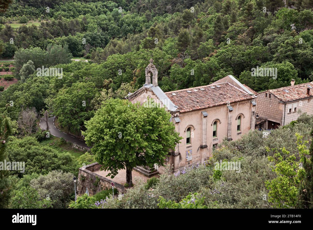 Lacoste, Vaucluse, Provence-Alpes-Costa Azzurra, Francia: Paesaggio dei boschi del parco naturale regionale del Luberon con la chiesa protestante Foto Stock